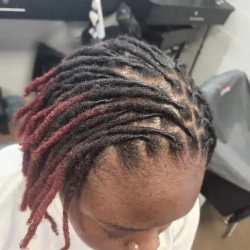 A woman with dreadlocks is wearing a white shirt.
