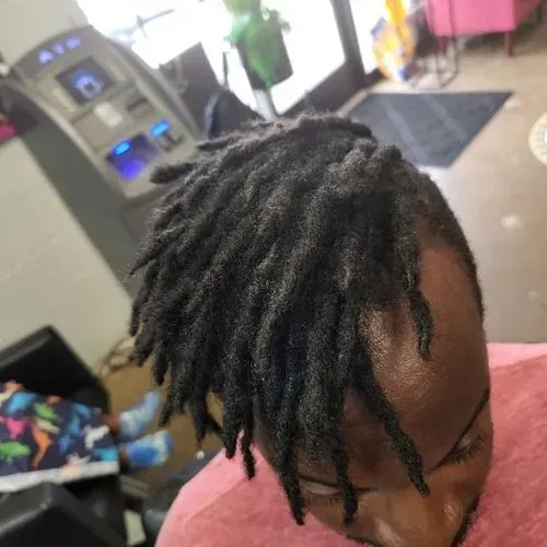 A woman with dreadlocks is sitting in front of an atm machine.