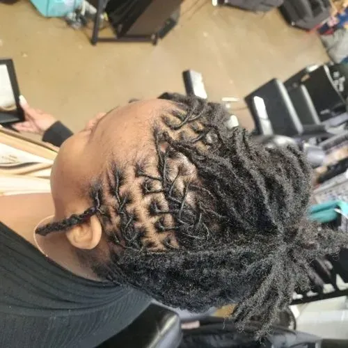 A woman with dreadlocks is sitting in a chair in front of a mirror.