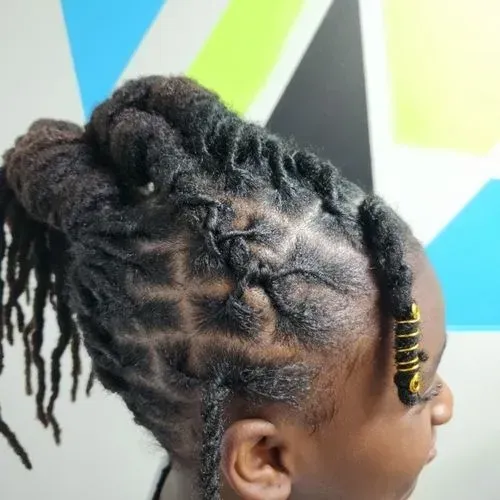 A young girl with dreadlocks is wearing a bun and earrings.
