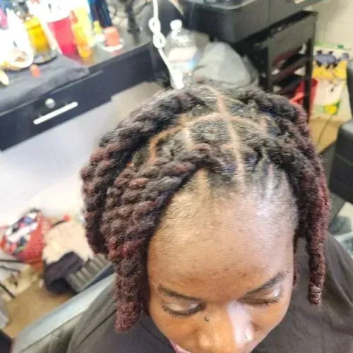 A woman with dreadlocks is sitting in a chair in a salon.