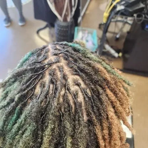 A close up of a person 's hair with dreadlocks in a salon.