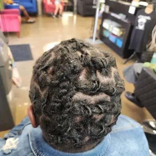 The back of a person 's head with dreadlocks in a salon.