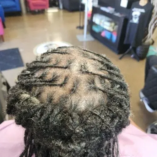 The back of a person 's head with dreadlocks in a salon.