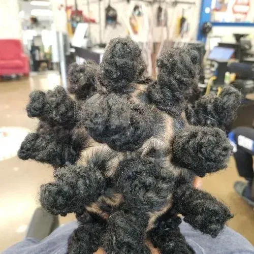 A person is holding a bunch of dreadlocks in their hair in a salon.
