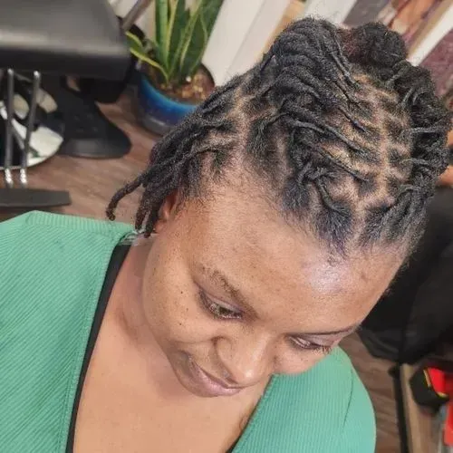 A woman with dreadlocks is wearing a green shirt.