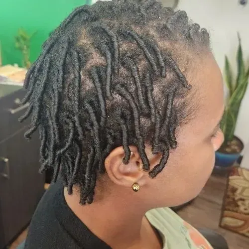 A woman with dreadlocks in her hair is sitting in a chair.