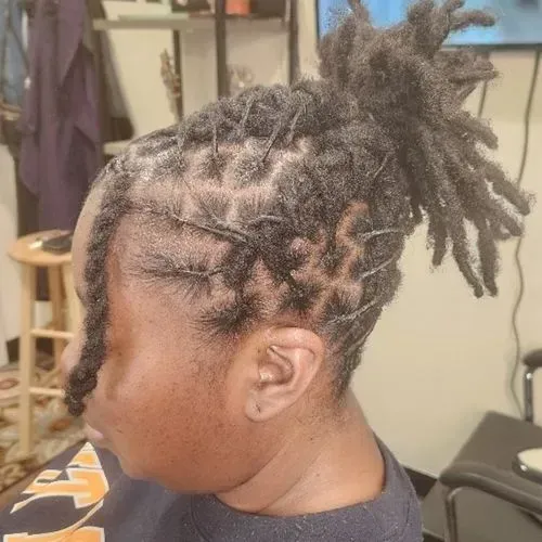 A woman with dreadlocks in a bun is sitting in a room.
