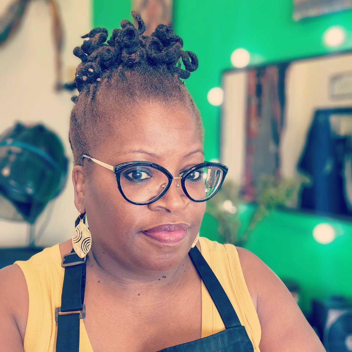 A woman wearing glasses and an apron is looking at the camera