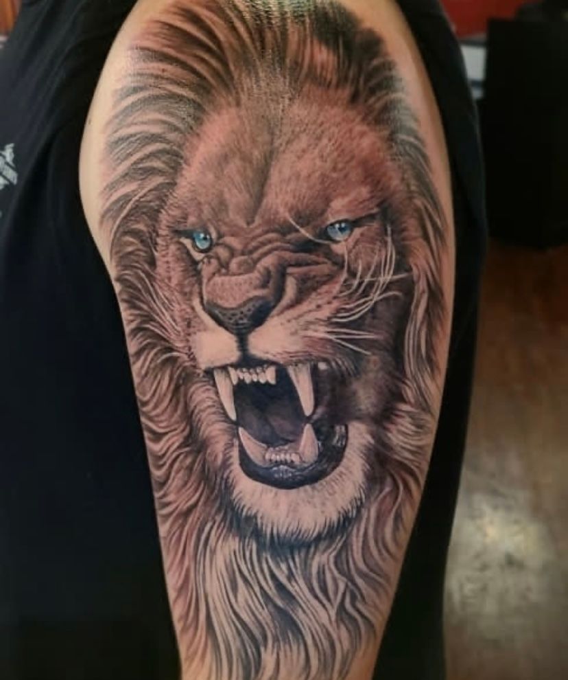 A man has a tattoo of a lion on his arm.