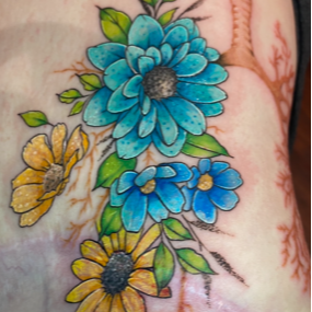 A close up of a tattoo of blue and yellow flowers