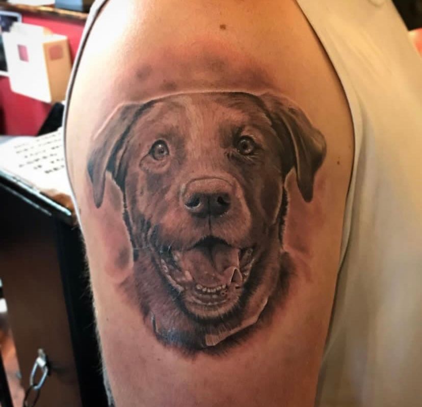 A man has a tattoo of a dog on his arm