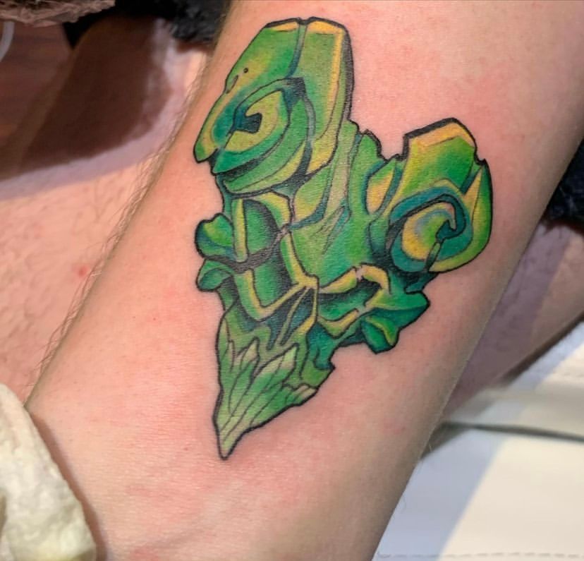 A person has a green heart shaped tattoo on their arm