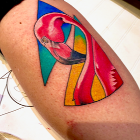 A person has a colorful flamingo tattoo on their arm