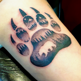 A person has a bear paw print tattoo on their arm