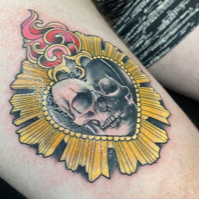 A tattoo of a skull in a heart on a person 's arm