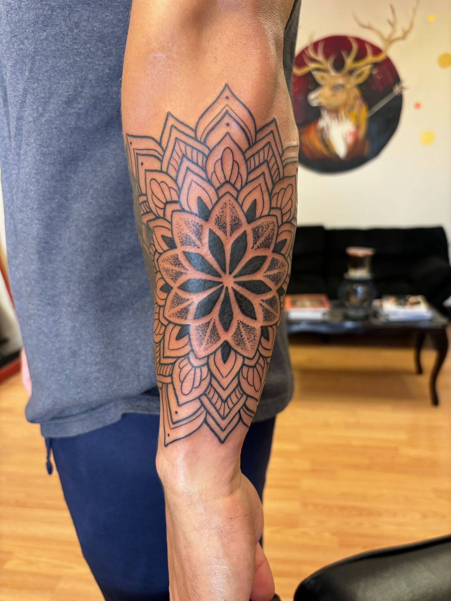 A man has a tattoo of a mandala on his forearm.