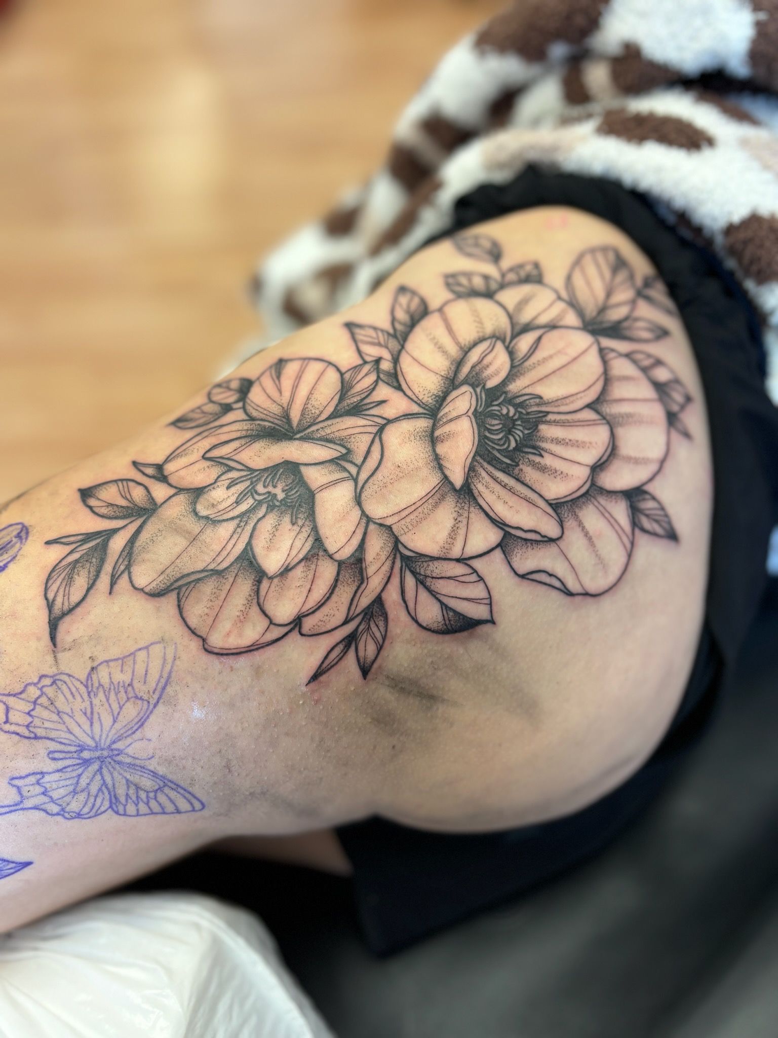 A woman has a tattoo of flowers and butterflies on her thigh.