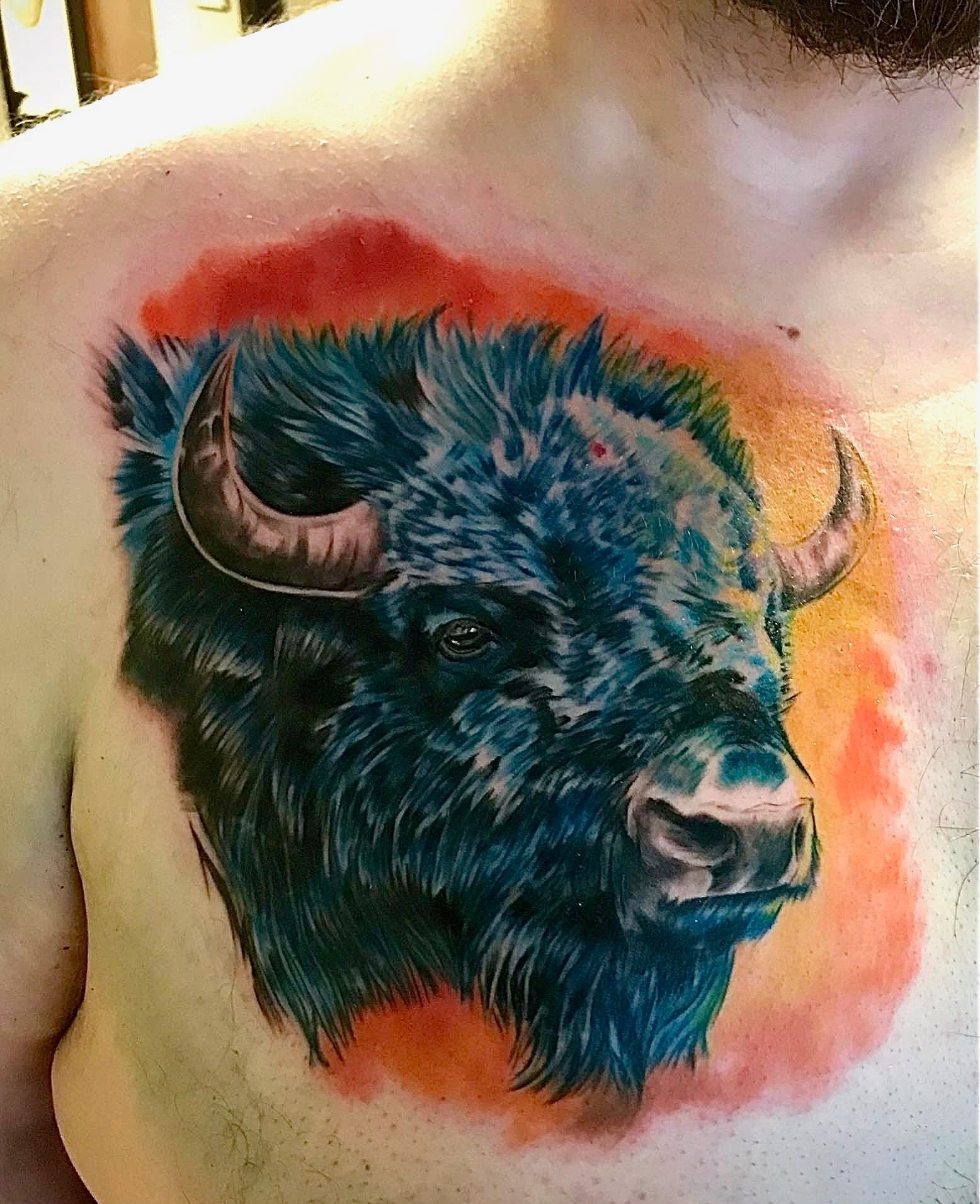 A man has a tattoo of a bison on his chest.
