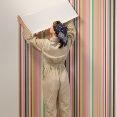 A female decorator hanging up colourful wallpaper