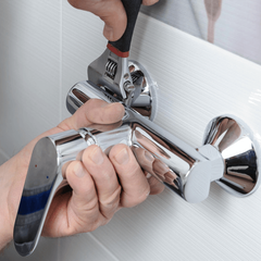 Man's hands fixing a shower faucet with a adjustable wrench.