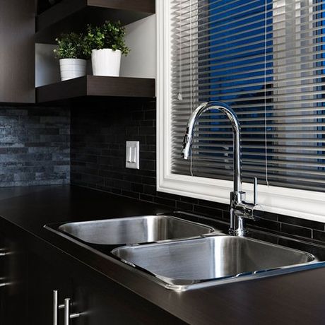 Stainless steel double kitchen sink in a dark brown kitchen