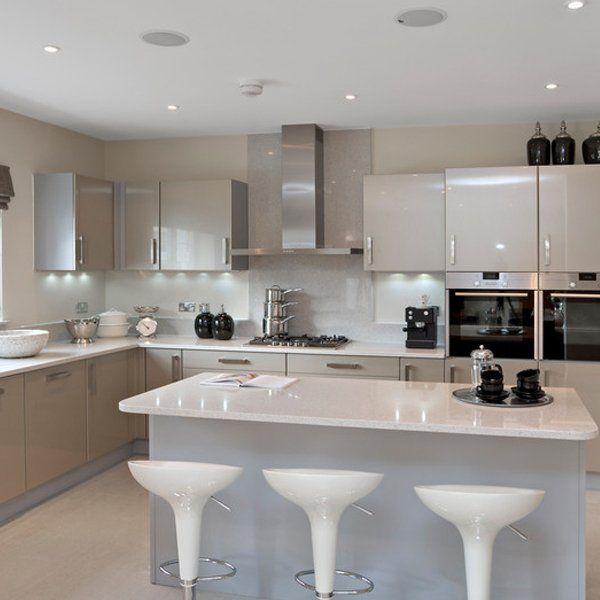 a spacious light grey coloured kitchen from a luxury new home featuring a large island and breakfast bar, plenty of cupboards, a modern hob with overhead extractor, twin ovens and a microwave.