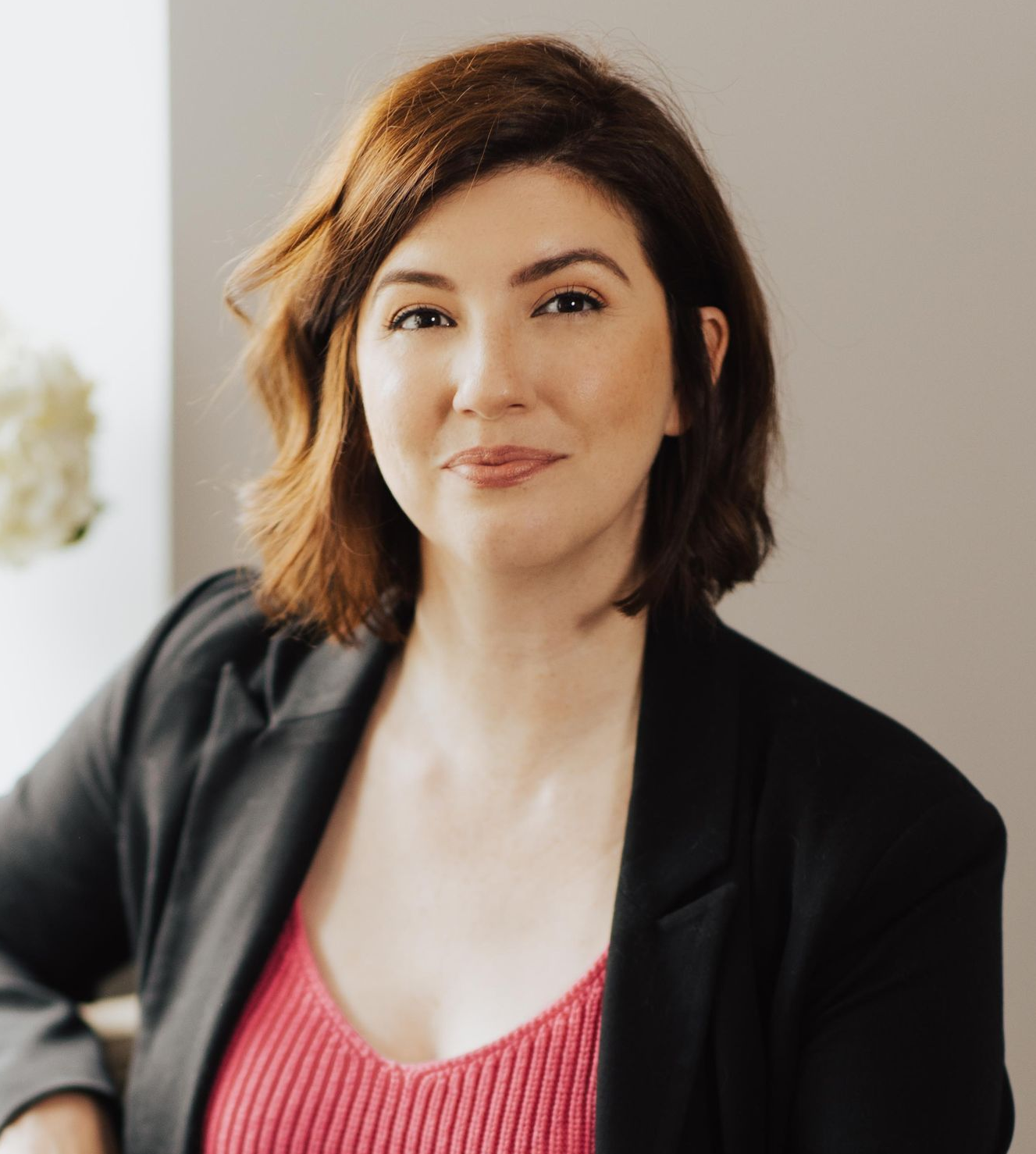 Woman with auburn hair in a black blazer, smiling.