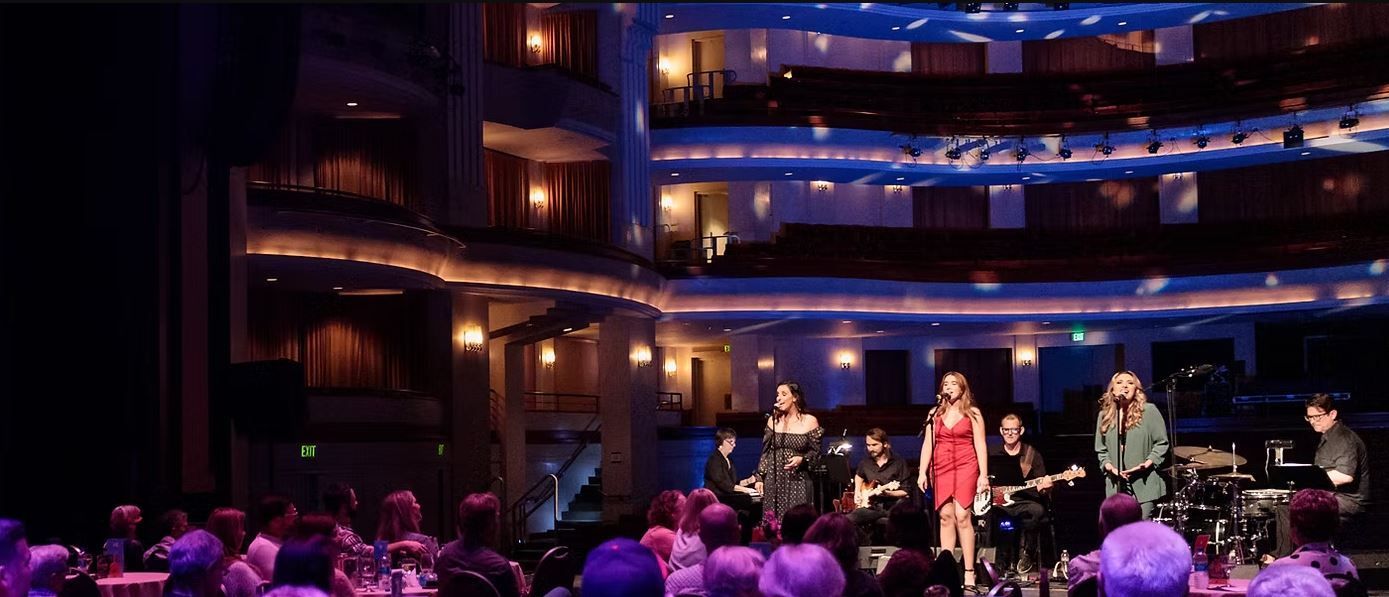 A musical performance on stage in a theater. Performers, stage lights, and audience.