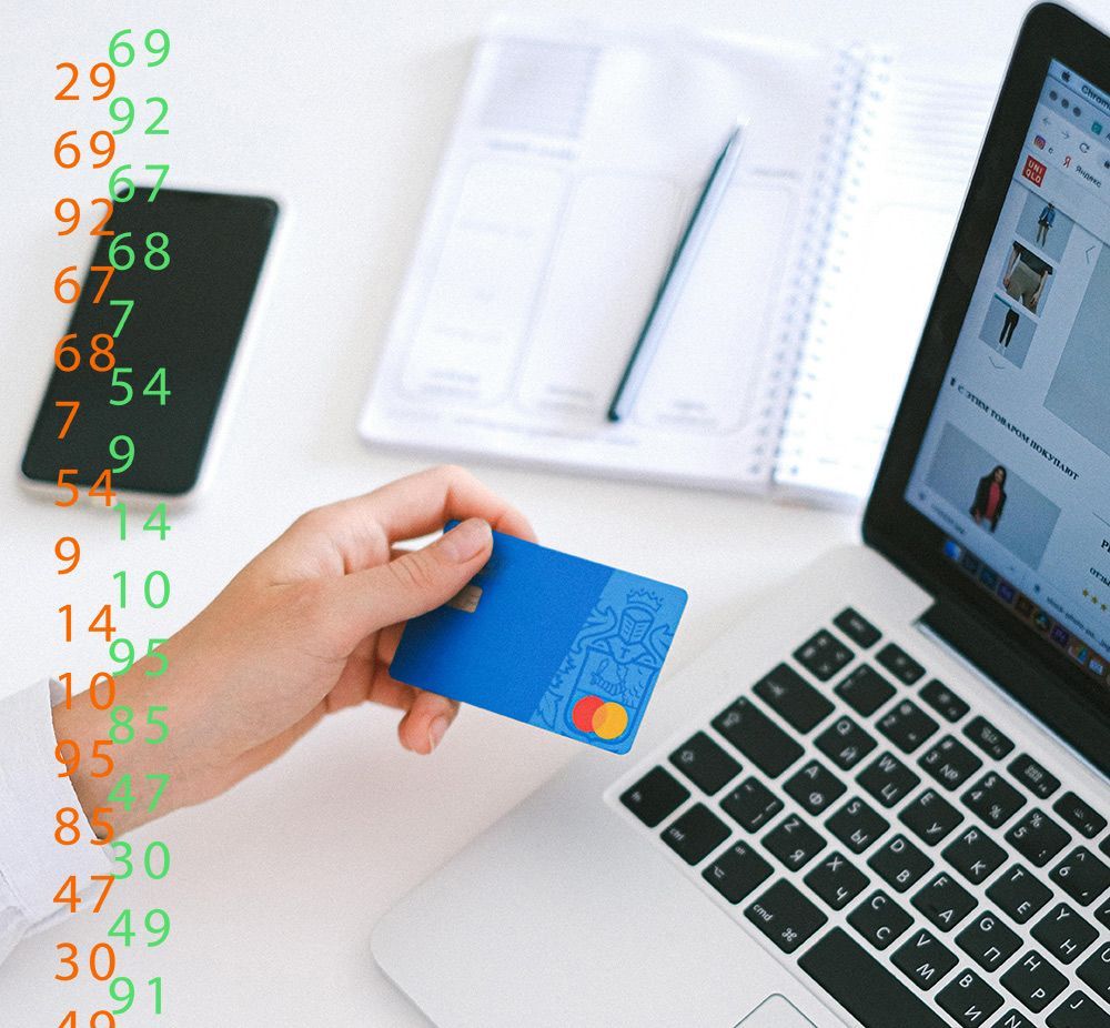 Une personne tient une carte de crédit bleue près d'un ordinateur portable et d'un carnet, symbolisant les achats en ligne ou les paiements numériques.
