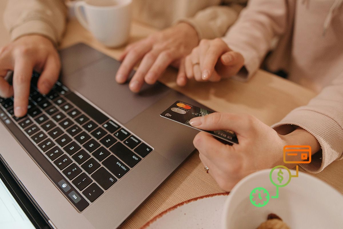 Deux personnes utilisent un ordinateur portable et une carte de crédit pour effectuer un paiement en ligne à une table.