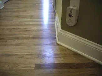 a wooden floor in a hallway with a remote control on the wall