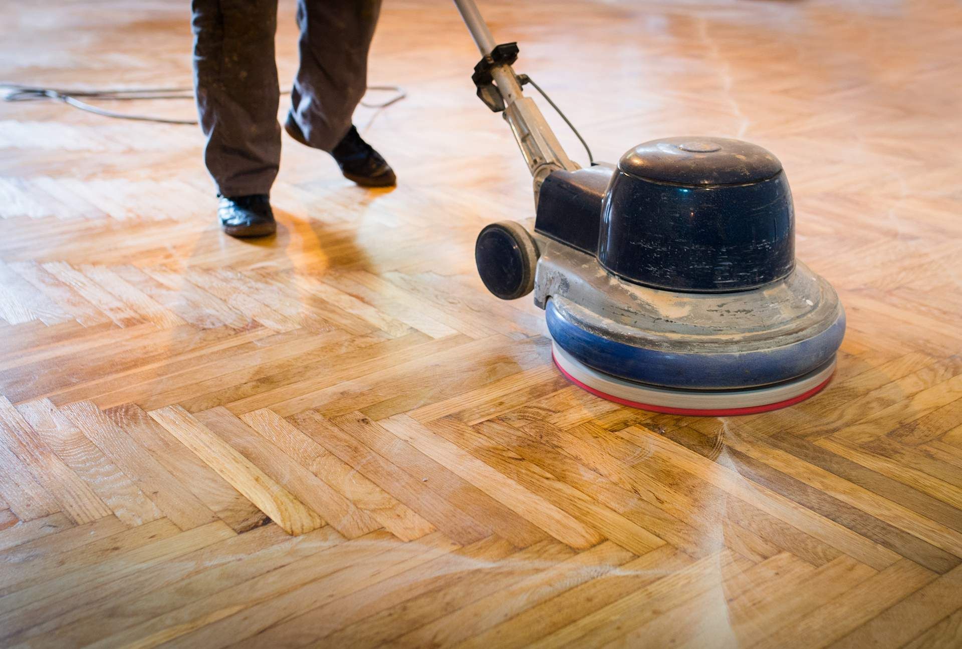 A person is polishing a wooden floor with a machine.