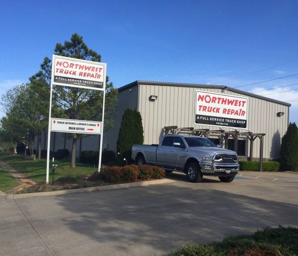 Northwest Truck Repair building with sign, silver truck parked outside on a sunny day.