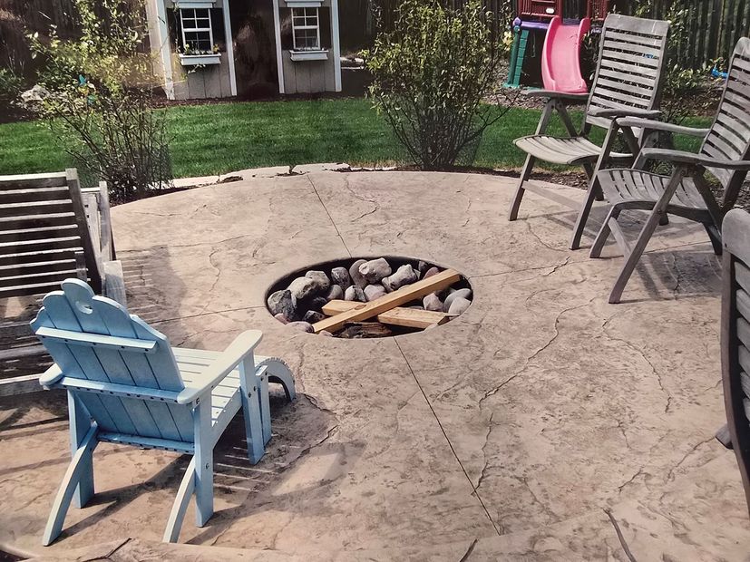 A patio with a table and chairs and a ceiling fan overlooking a pool.