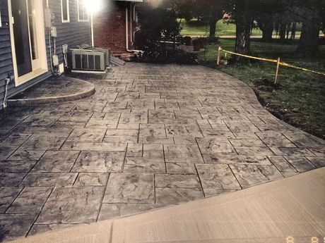 A brick walkway with a pond in the middle of it.