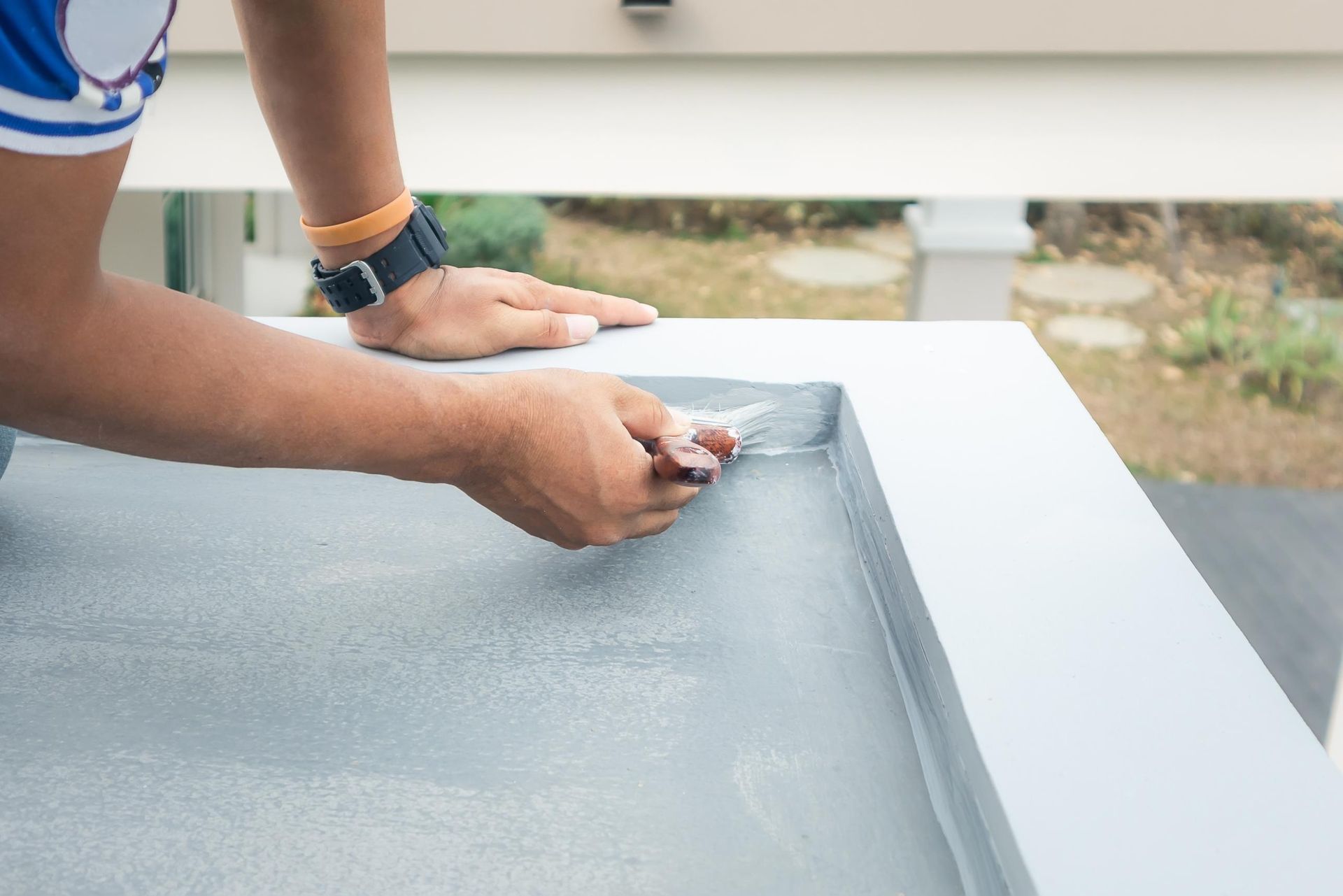 A man is painting a concrete surface with a spatula.