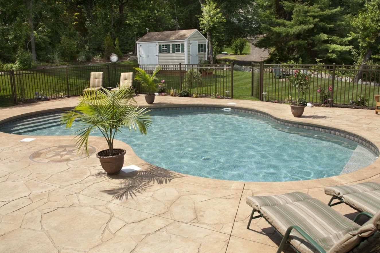 A large swimming pool with chairs and a shed in the background.