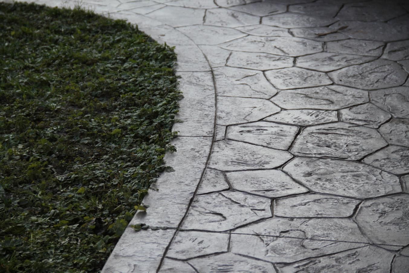 A concrete walkway going through a grassy area.