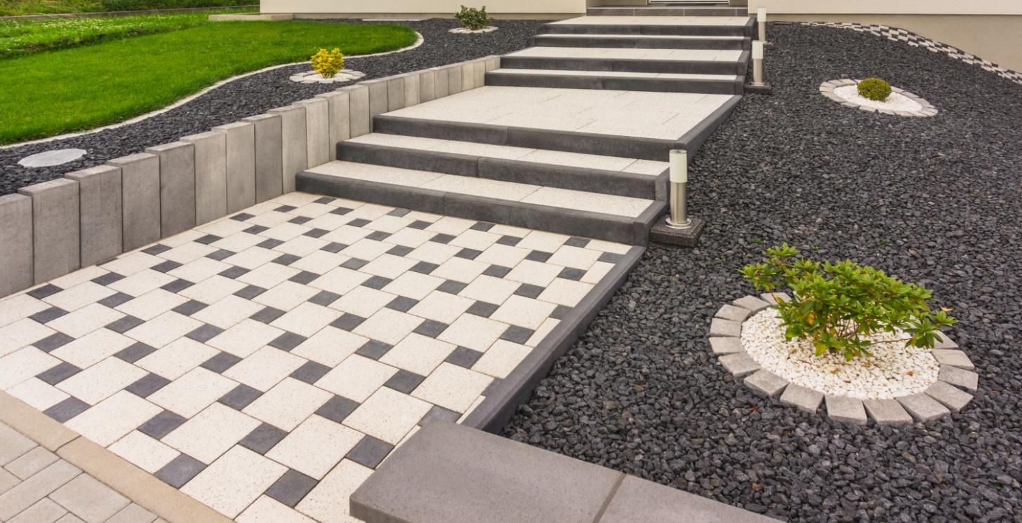 A brick walkway with stairs and gravel in a garden.