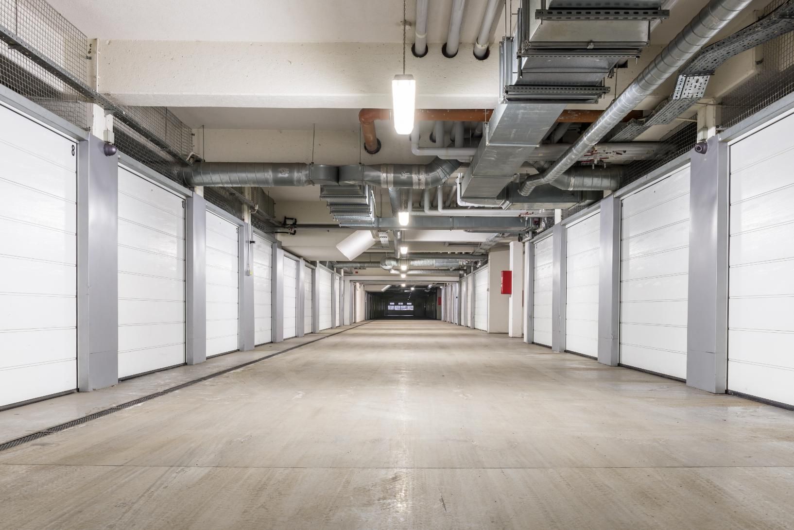 A long empty parking garage with white garage doors.