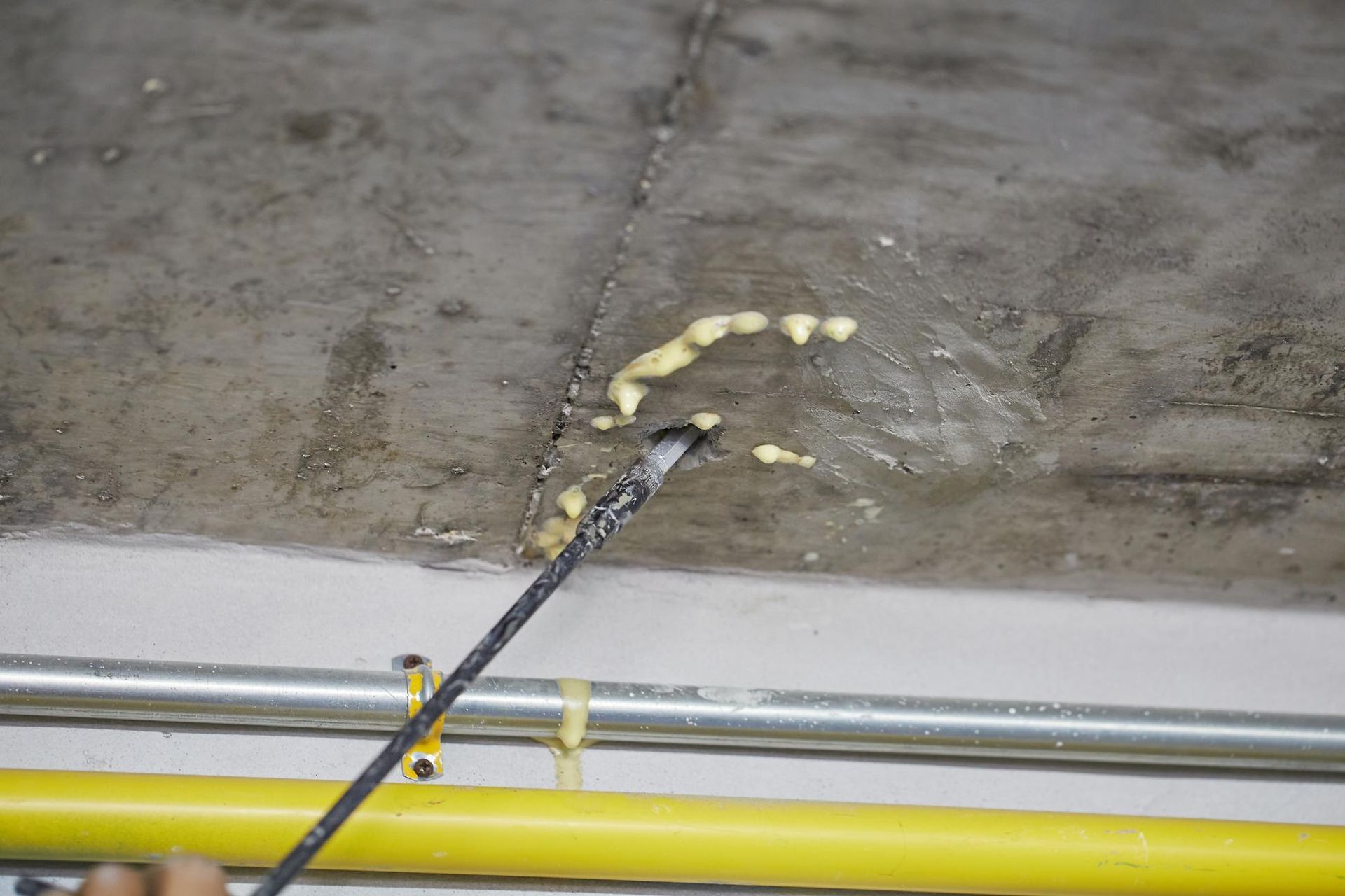 A person is spraying foam on a concrete floor.