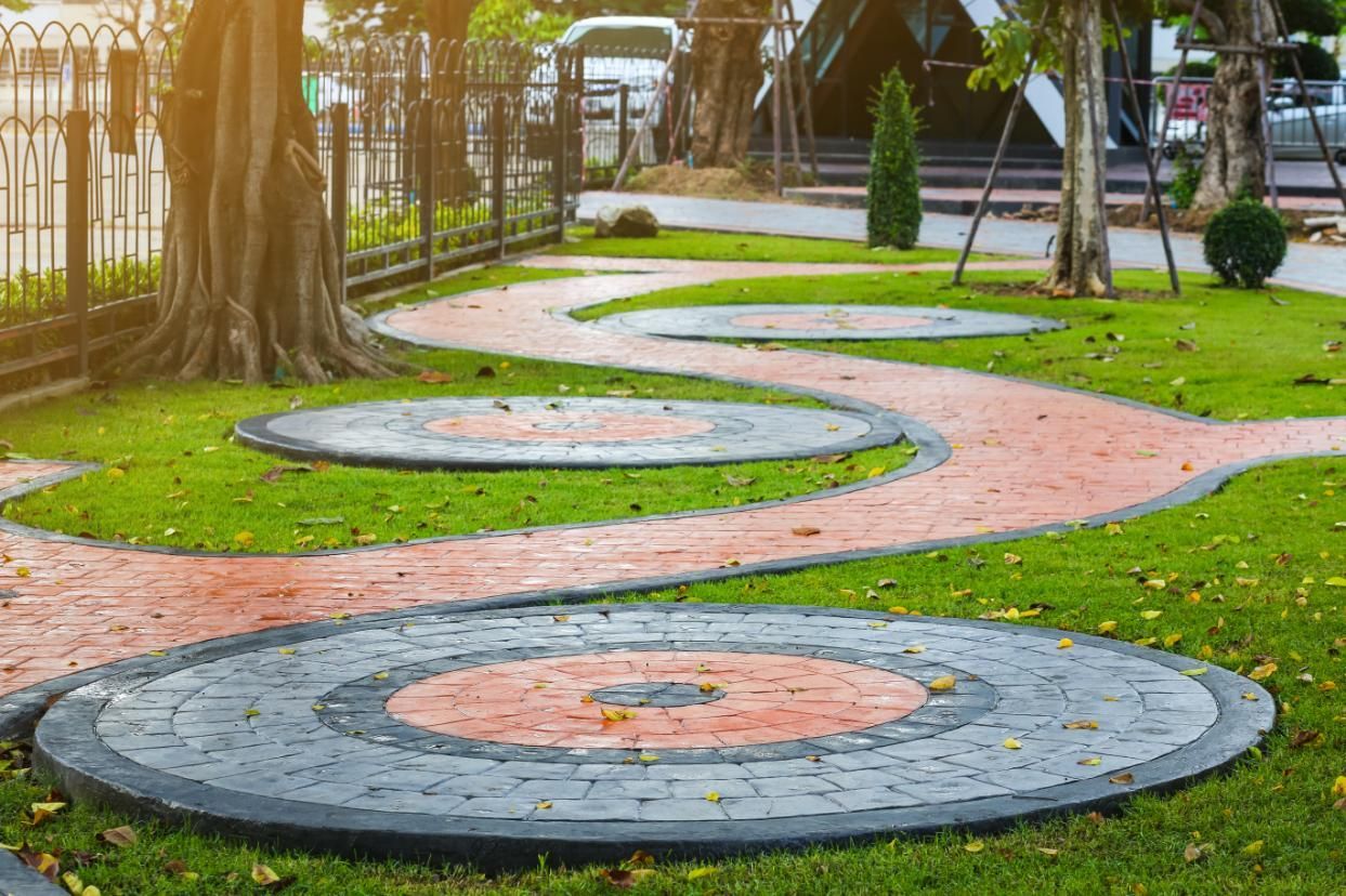 A brick walkway surrounded by grass and trees in a park.