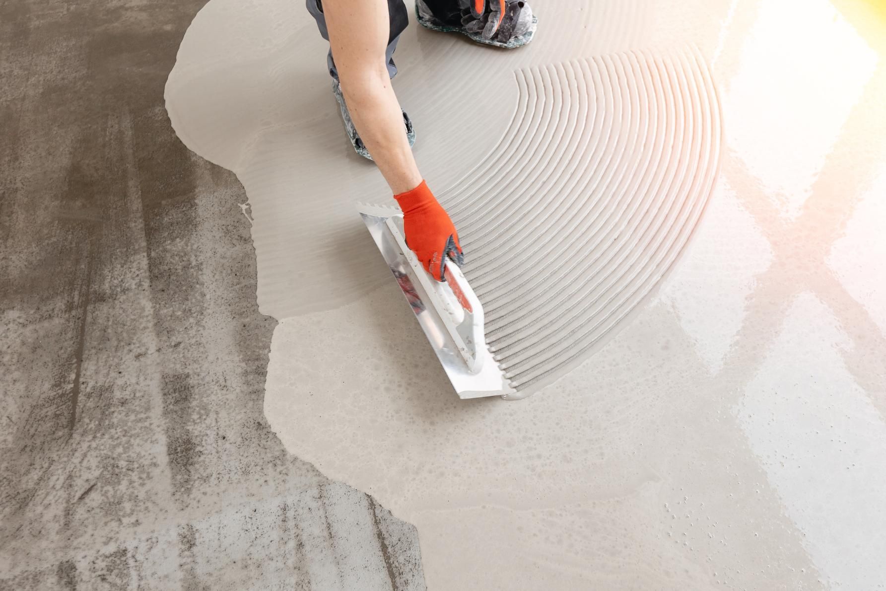 A person is spreading a concrete floor with a trowel.