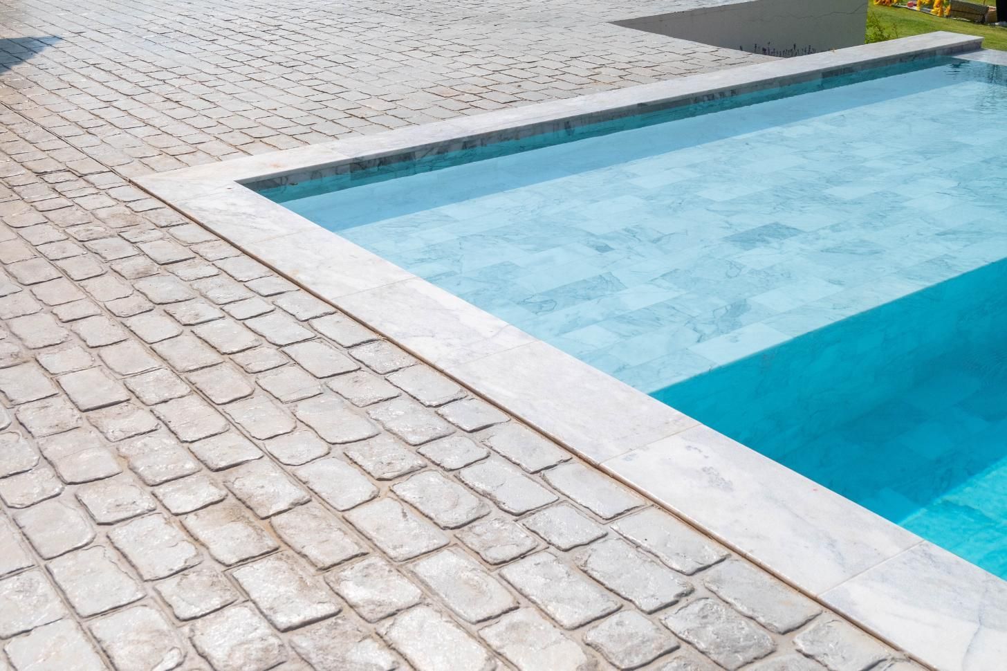 A swimming pool with a brick walkway surrounding it