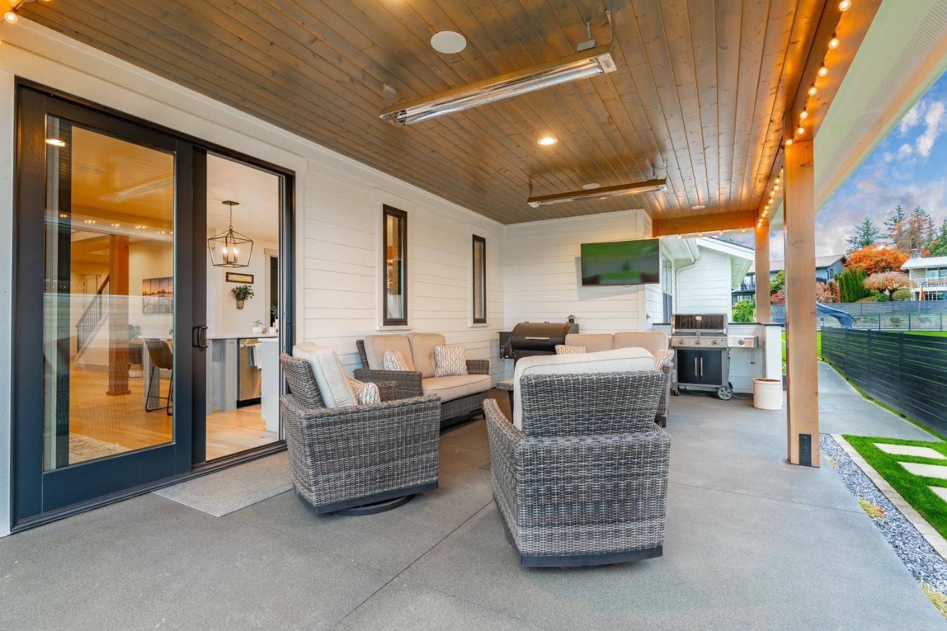 A patio with a couch, chairs, and a grill.