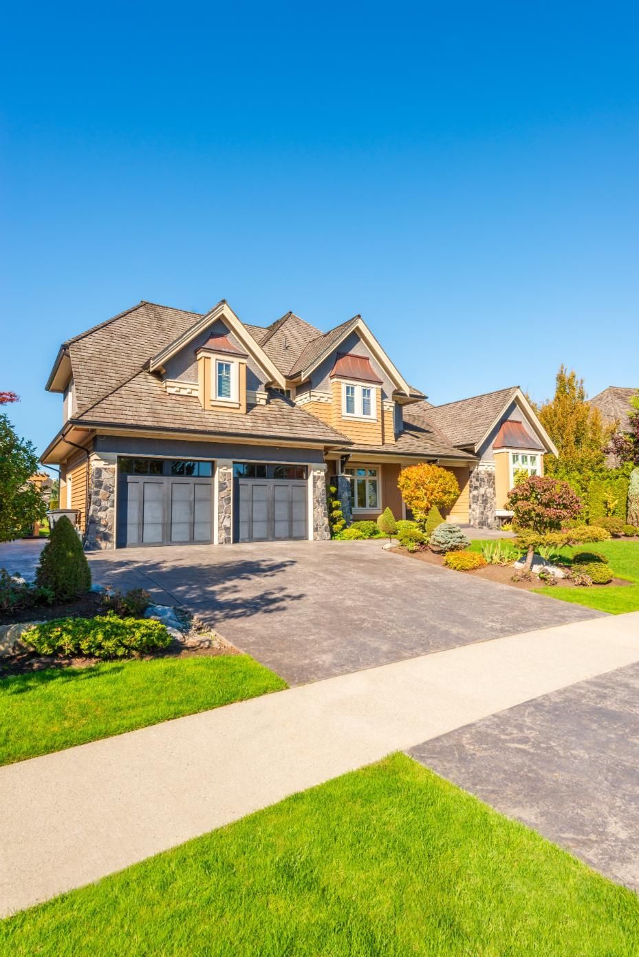 A large house with a large driveway and a lush green lawn.