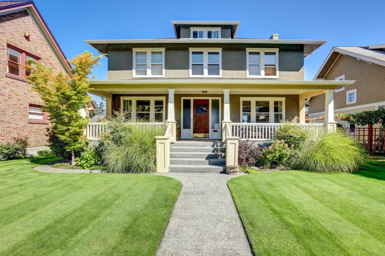 A large house with a lush green lawn and a walkway leading to it.