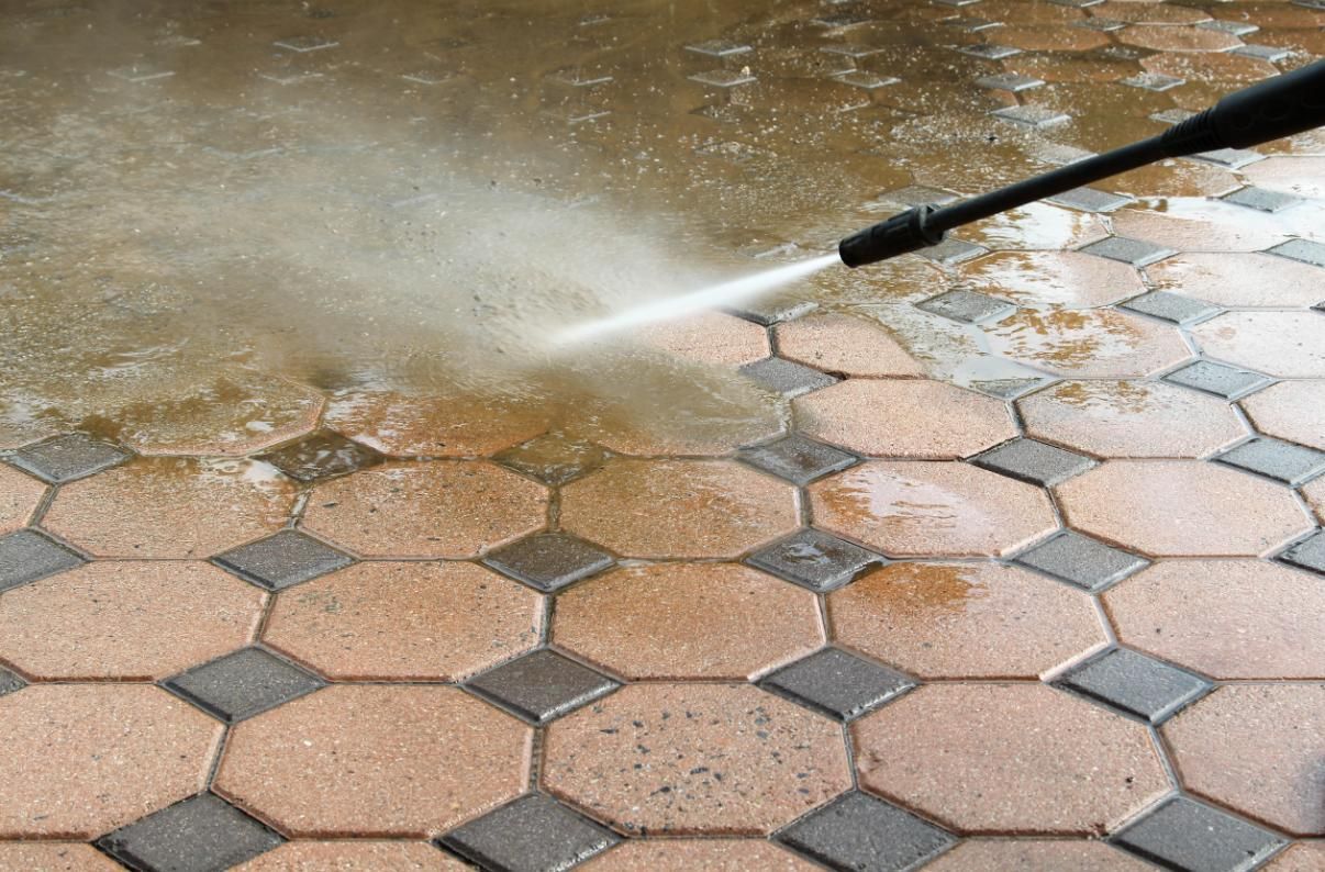 A person is using a high pressure washer to clean a tiled floor.