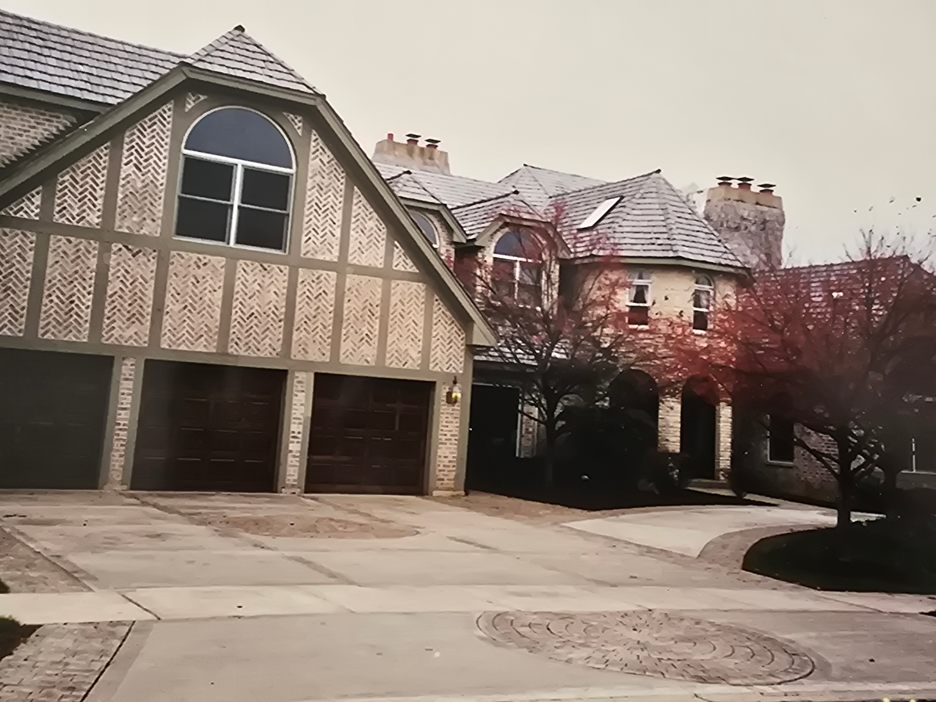 A large house with a lot of garages and trees in front of it.